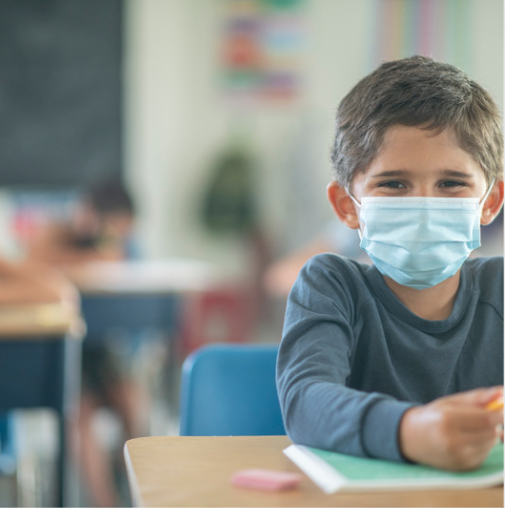 Little boy in kindergarten with mask on due to coronavirus pandemic